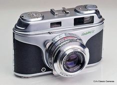 an old fashioned camera sitting on top of a white table with the lens pointed up