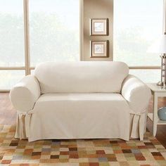 a white couch sitting on top of a living room floor next to a lamp and window