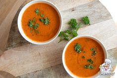 two bowls of tomato soup with parsley on top