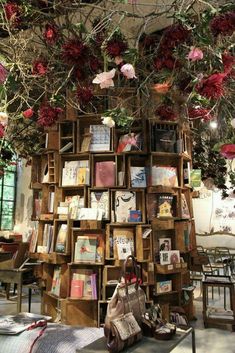 there is a book shelf with many books on it and flowers hanging from the ceiling