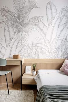 a bed sitting under a palm tree wallpaper next to a desk with a chair