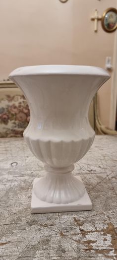 a white vase sitting on top of a table