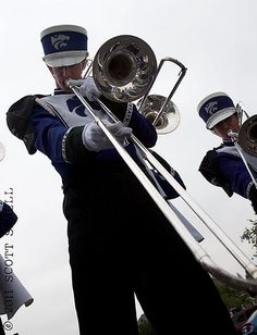 a marching band is performing in front of the crowd with their instruments and trumpets up to their ear