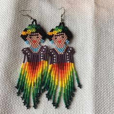 the beaded earrings are colorful and have two women in them, one is wearing a hat