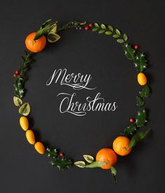 a merry christmas card with oranges and greenery on a black background that says merry christmas