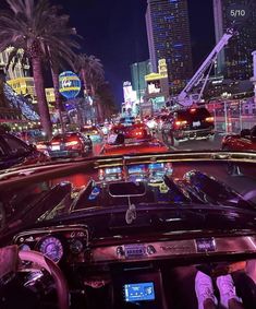 a city street filled with lots of traffic next to tall buildings and palm trees at night