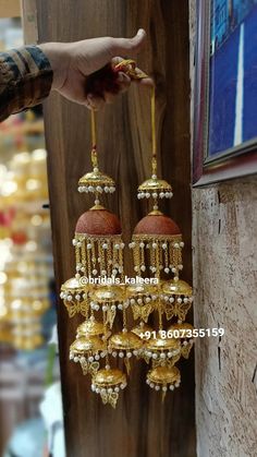 a person is holding up some gold earrings