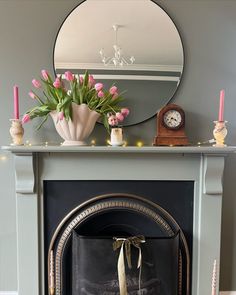 a fireplace with a mirror and flowers on top