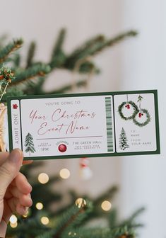 someone holding up a christmas gift card in front of a tree