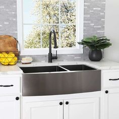 a stainless steel kitchen sink in front of a window