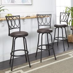 three black barstools in front of a counter with potted plants on it