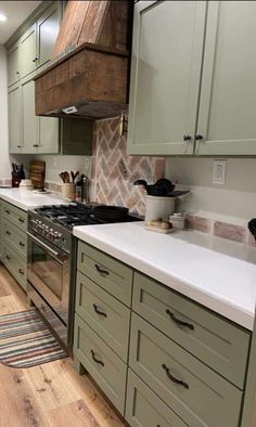 a kitchen with green cabinets and white counter tops, wood flooring and an oven