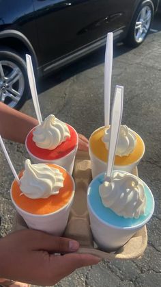 there are four ice cream sundaes on the tray in front of a car