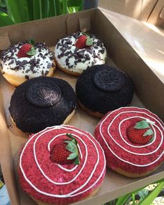 six donuts in a box with different toppings and strawberries on the top