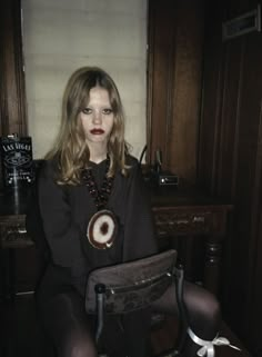 a woman sitting on top of a chair in front of a desk with a clock