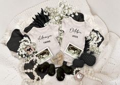 two white onesuits are sitting on a lace doily with baby's breath