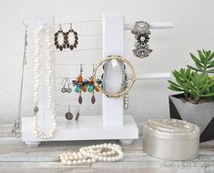 jewelry is displayed on a white shelf next to a potted plant and necklaces