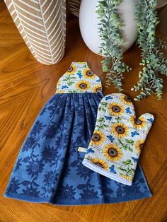 two sunflowers are on the table next to a potted plant and oven mitts