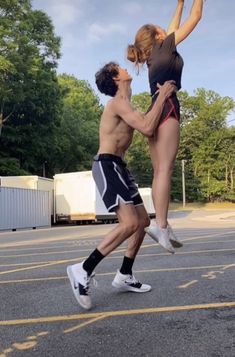 two people jumping in the air to catch a frisbee on a parking lot