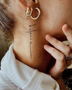 a woman with a cross tattoo on her neck is holding her hand to her ear