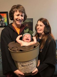 a man and woman holding a baby in a bath tub with leaves on it's head