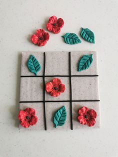 some red flowers and green leaves on a white tile background with black squares in the middle