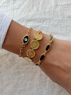 Three Women Bracelets in gold color that are made with stainless steel chains. The first bracelet has an oval evil eye charm with black enamel. The second bracelet has ethnic discs in a row, and the last bracelet has five rectangular charms with black enamels that complete this really special set. You can wear them separetely or as a set as well.  Find them only at Christina Christi Store 👉 My Women Bracelets Collection: https://etsy.me/2U57si7 👉 Express Shipping: https://etsy.me/3ikUnOM MATER Evil Eye Bracelet Gold, Bracelet Evil Eye, Women Bracelets, Disc Bracelet, Three Women, Gold Armband, Gold Bead Bracelets, Chunky Jewelry, Homemade Jewelry