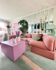 a living room filled with pink couches and pillows