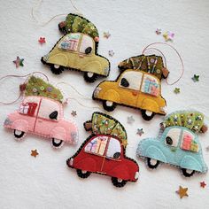 four small cars are hanging from strings on a white surface with stars and confetti