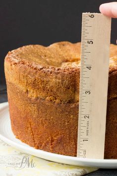 a person measuring the height of a cake on a plate with a ruler in front of it