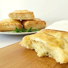 some food is laying on a wooden cutting board next to a plate with pastries