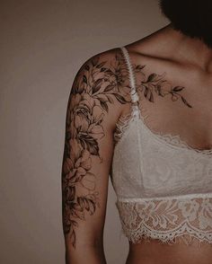 a woman with tattoos on her arm and shoulder is wearing a bra top that has flowers on it