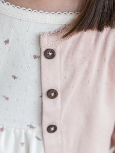 a close up of a person wearing a pink shirt with buttons on the collar and sleeves