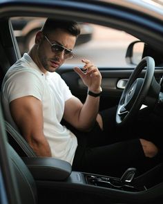 a man sitting in the driver's seat of a car talking on his cell phone