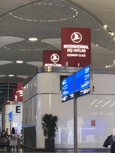 people are walking through an airport terminal with signs on the wall and in front of them