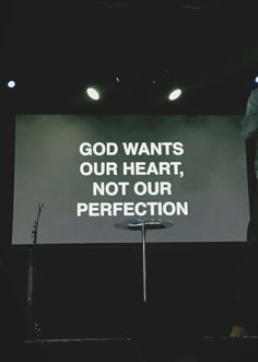 a man standing in front of a projection screen that says god wants our heart, not our perfectionion