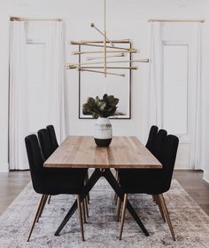 a dining room table with black chairs and a white rug