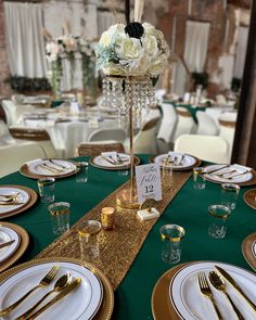 the table is set with gold and white plates, silverware, and centerpieces