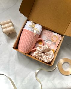 a pink coffee mug sitting inside of a box next to some other items on a table