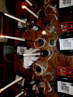 a wooden table topped with lots of black plates and silverware covered in white feathers