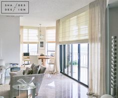 a living room filled with furniture next to a window covered in blinds and drapes