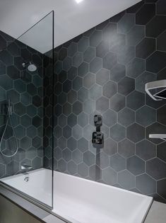 a modern bathroom with hexagonal tiles on the wall and bathtub in the corner