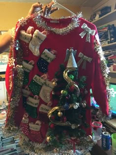 a red sweater with christmas decorations hanging from it's sides and on the front