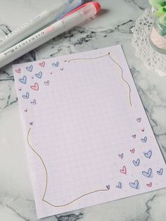 a notepad with hearts on it next to two markers