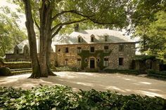 an old stone house surrounded by greenery and trees in the middle of a park