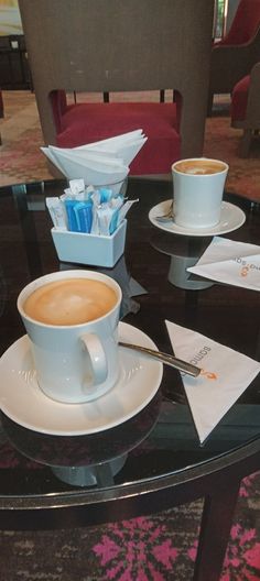 two cups of coffee on a glass table