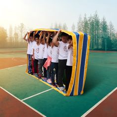 a group of young children standing on top of a tennis court covered in a tarp