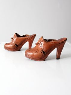 "This is a pair of 1970s vintage clogs by Brasil. The brown leather high heel mules feature cut out design and leather tie details. CONDITION In good condition with wear consistent with age and use. Leather is splitting slighting from wood at heel on one shoe. Marked Size: 6 US MEASUREMENTS Insole Length: 9 .. 22.9 cm Width: 2.5\" .. 6.4 cm Wall to Toe Length: 8.5\" .. 21.6 cm Heel: 4.25\" .. 10.8 cm 82159" Retro Brown Closed Toe Mules, Vintage Brown Mules With Leather Sole, Vintage Brown Heels With Wooden Heel, Vintage Brown Heels With Leather Sole, Formal Brown Clogs With Wooden Heel, Vintage Brown Leather Mules, Brown Leather Clogs With 4-inch Heel, Retro Closed Toe Leather Mules, Retro Leather Closed Toe Mules