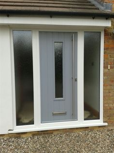 a grey double door in front of a brick building with white trim on the side