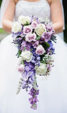 a bride holding a bouquet of purple and white flowers